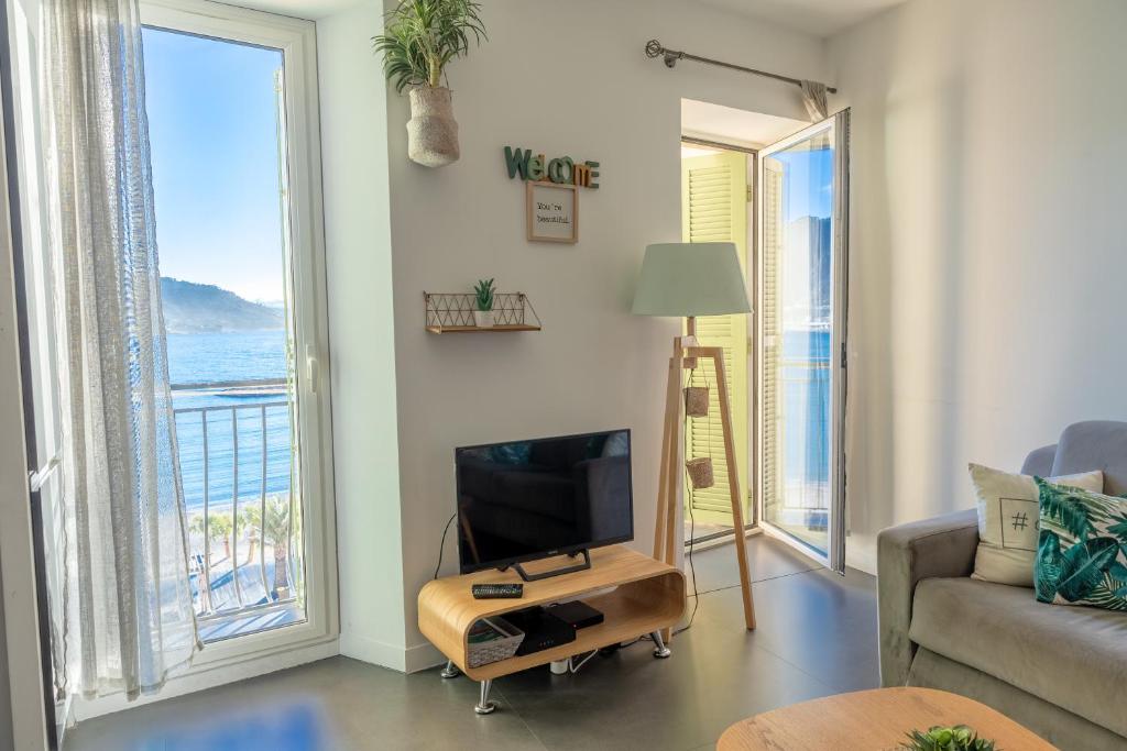 a living room with a tv and a view of the ocean at Les Sablettes in Menton