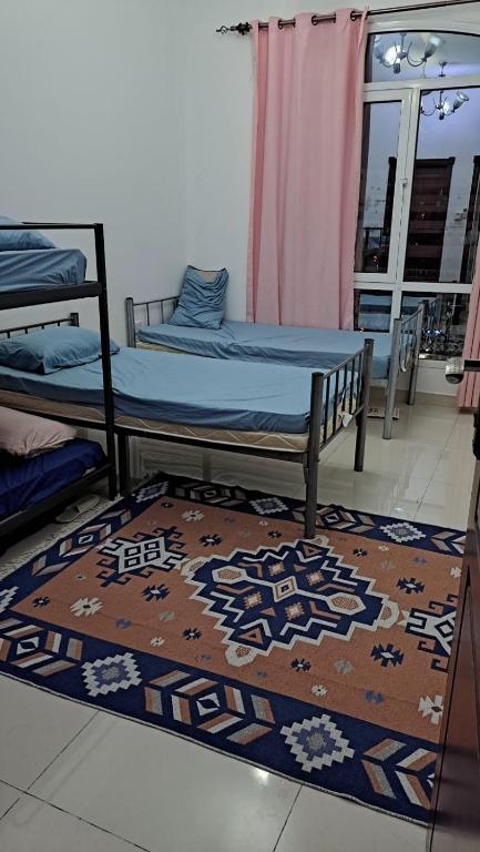 a bedroom with two beds and a rug on a floor at New mohastel in Muscat