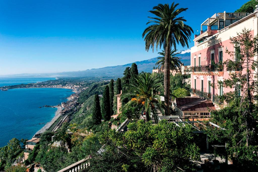 a beach with palm trees and palm trees at Hotel Villa Schuler in Taormina