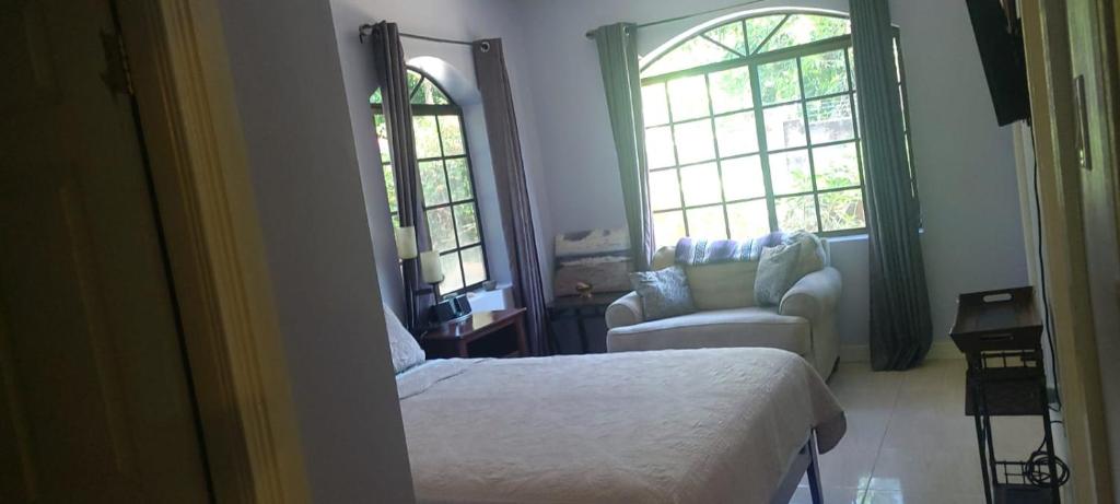 una camera con letto, sedia e finestre di Private Lodge, Cousin's Cove a Green Island
