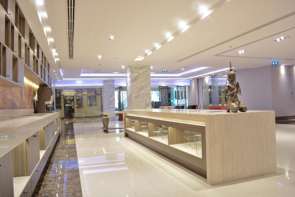 Contemporary lobby with a long illuminated display counter and Thai statue.