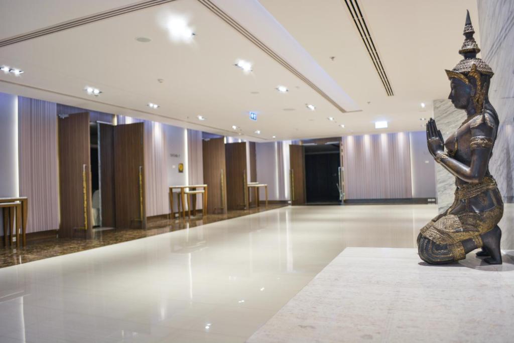Thai statue displayed beside elevator doors in a quiet hotel lobby area.