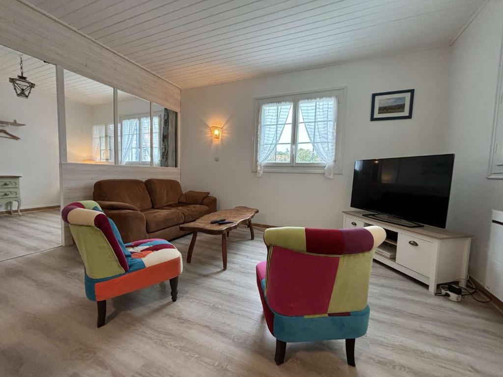 - un salon avec un canapé, une télévision et des chaises dans l'établissement Mais 4 pièces Oléron 6 couchages SAINT-PIERRE D'OLERON SPO000-099, à Saint-Pierre-dʼOléron