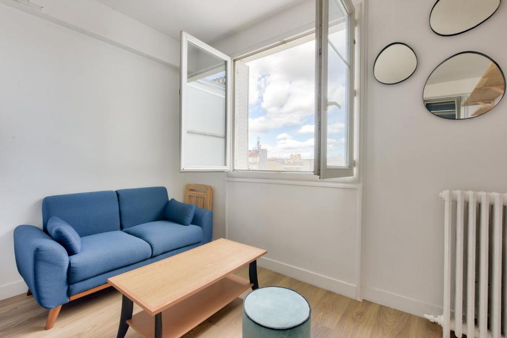 un salon avec un canapé bleu et une table dans l'établissement Splendide studio proche de la station métro Lourmel, à Paris