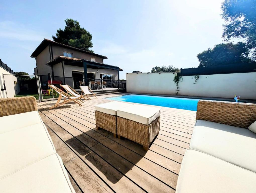 a deck with a pool and chairs next to a house at Villa plein Sud, clim et piscine, 6 à 8 personnes in Boisseron