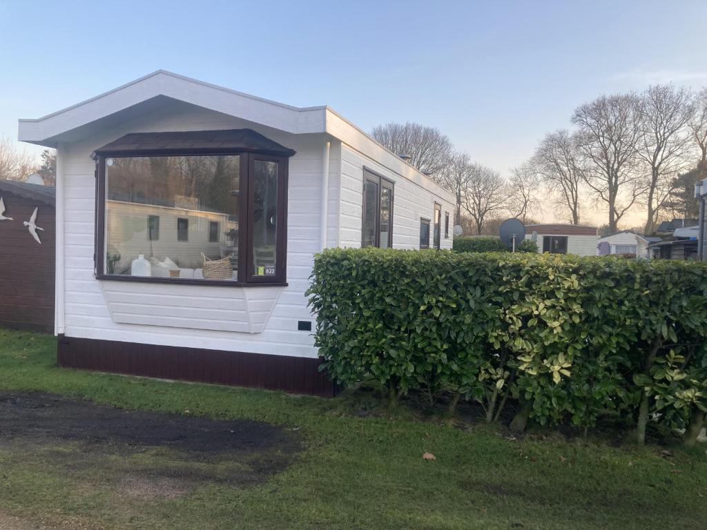 a small white house with a window in a yard at KD 822 - Vakantiepark Kijkduin in The Hague