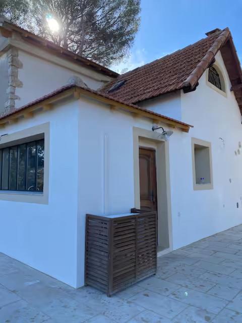 une maison blanche avec une porte en bois devant elle dans l'établissement Le studio de la Bonne Aventure, à Saint-Mitre-les-Remparts