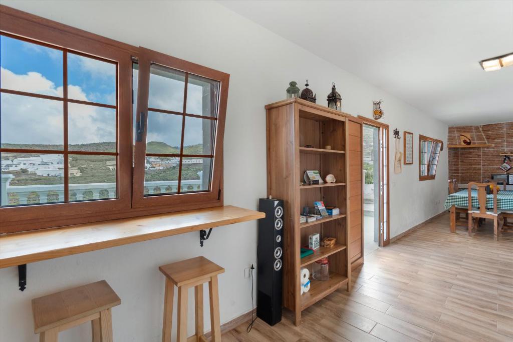 a living room with a table and some windows at Cueva la Umbría Artenara Vacacional in Artenara
