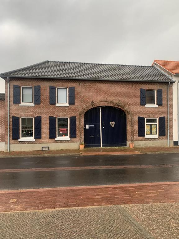 a brick building with a black door on a street at Althuizenhof - Jelle in Doenrade