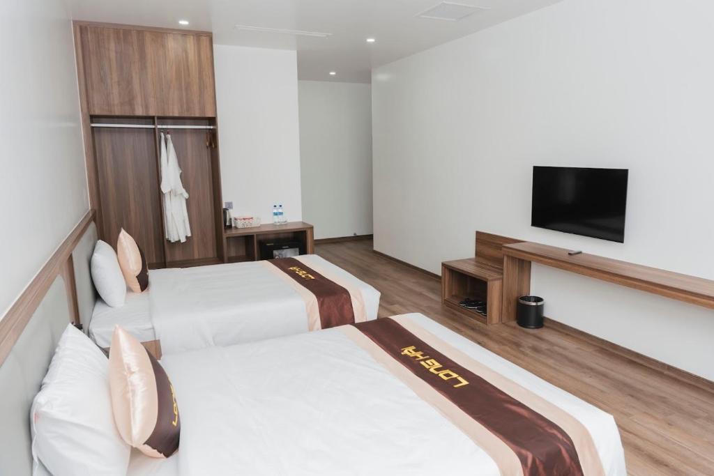 um quarto de hotel com duas camas e uma TV de tela plana em Long Hải Hotel em Móng Cái