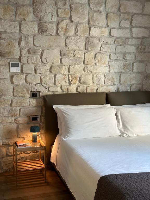 sypialnia z białym łóżkiem i ceglaną ścianą w obiekcie Olivia Rooms Eurialo w mieście Belvedere