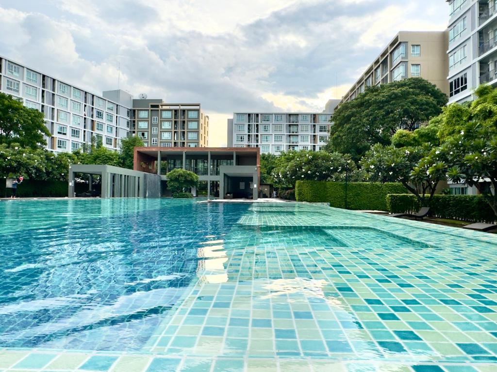a large swimming pool with blue tiles in front of buildings at Dcondo Near the Mall,Doi Suthep View in Chiang Mai
