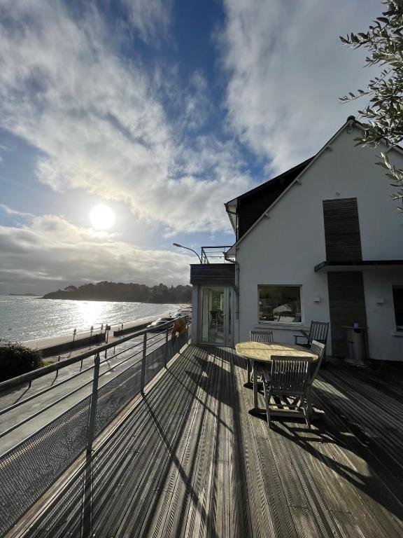une terrasse en bois avec une table et un banc sur une maison dans l'établissement Maison - Les Embruns - Vue mer, à Cancale