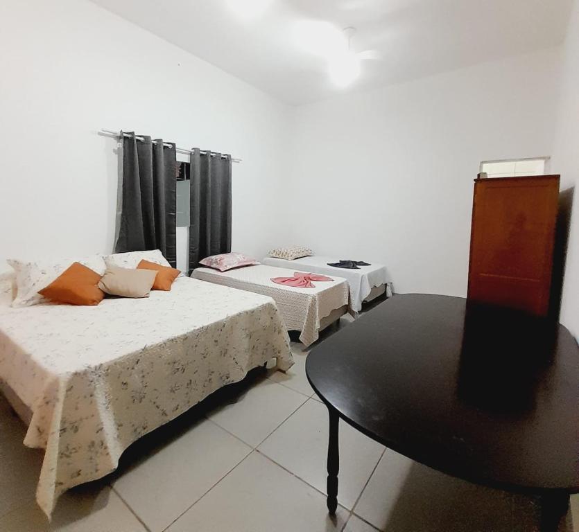 a room with two beds and a table in it at CASA - 7 quartos - 10 vagas de garagem in Campo Grande