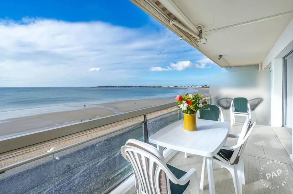 a table and chairs on a balcony with a view of the beach at Appartement avec vue sur la mer à La Baule 62 m² tout équipé in La Baule