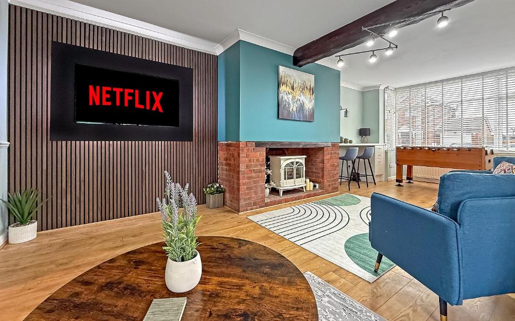 a living room with a blue couch and a fireplace at SPACIOUS STYLISH HOME, Foosball Table, FREE PARKING, Driveway, Garden & LAUNDRY ROOM, 2 DOUBLE BEDROOMS & LED Media wall in Luton