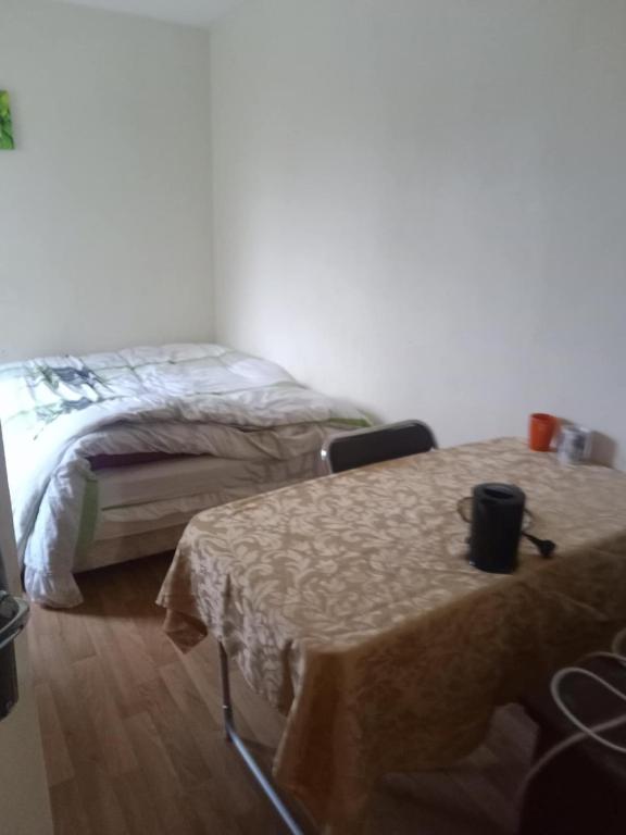 a room with two beds and a table and a chair at chambre à louer en nuité in Le Mans