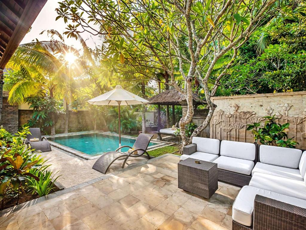 a patio with a white couch and a pool at Sofitel Bali Nusa Dua Beach Resort in Nusa Dua