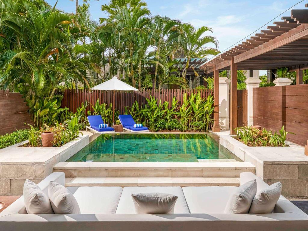 a swimming pool in a backyard with blue chairs at Sofitel Bali Nusa Dua Beach Resort in Nusa Dua