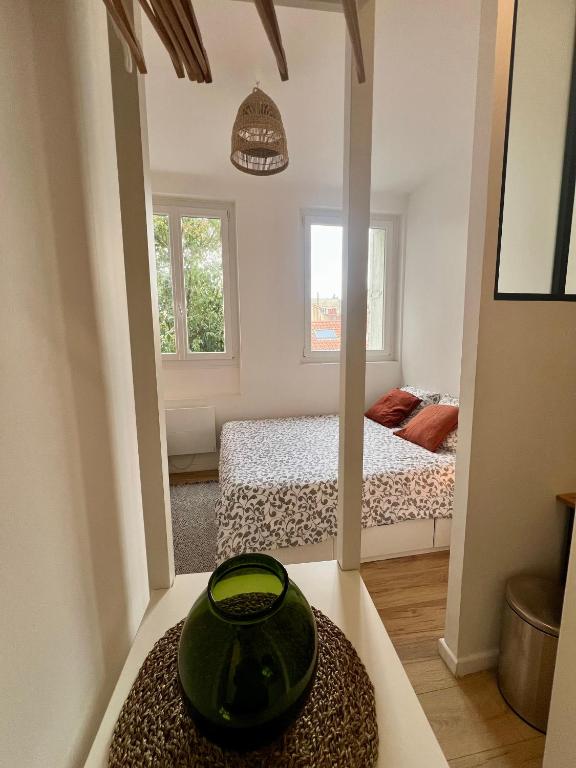 - une petite chambre avec un vase vert sur une table dans l'établissement Laa Conciergerie, l'écrin vert des Chalets, à Toulouse