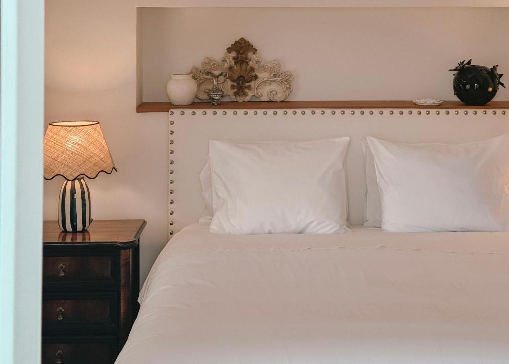 a bedroom with a bed with white pillows and a lamp at Quinta Amarela - B&B in Nazaré