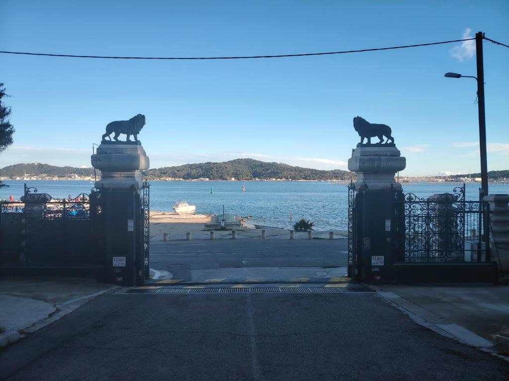 d'une porte avec deux statues de chats sur elle et offrant une vue sur l'eau dans l'établissement Tamaris Studio, Pool & Beach, à La Seyne-sur-Mer