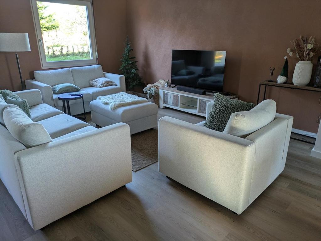 - un salon avec trois canapés et une télévision dans l'établissement Gîte des Petits Prés, à La Neuville-aux-Joûtes