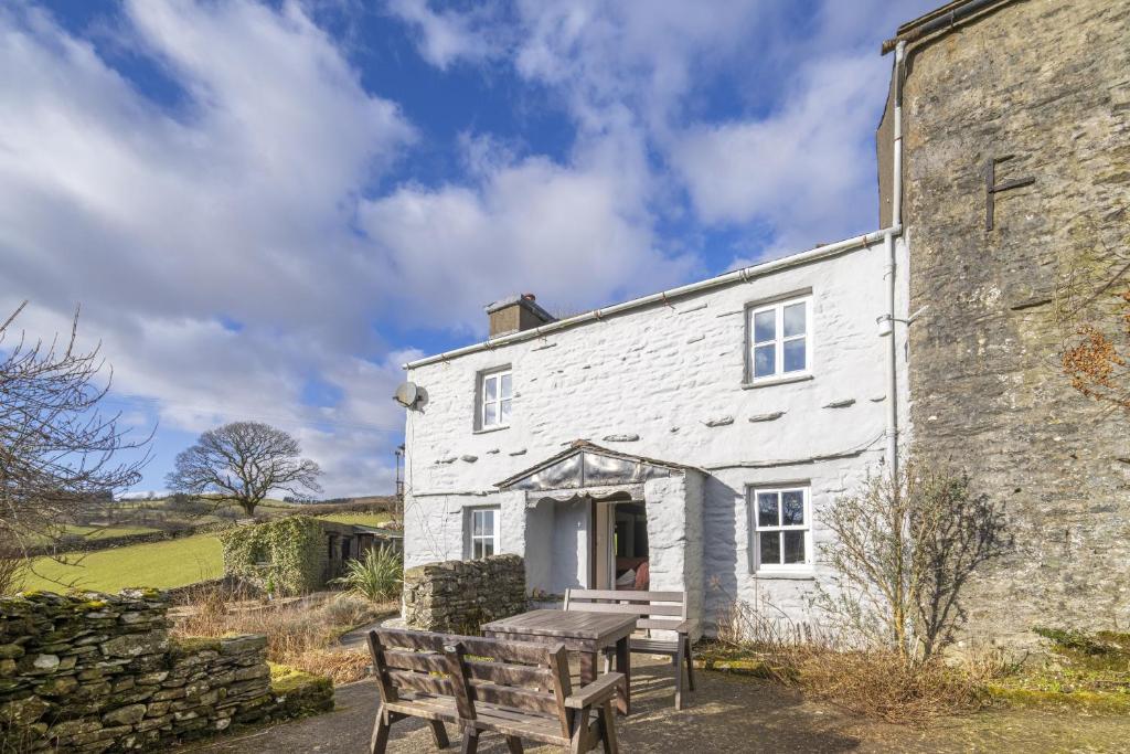 una casa bianca con un tavolo da picnic di fronte di Drawell Cottage - Situated on a working farm a Sedbergh
