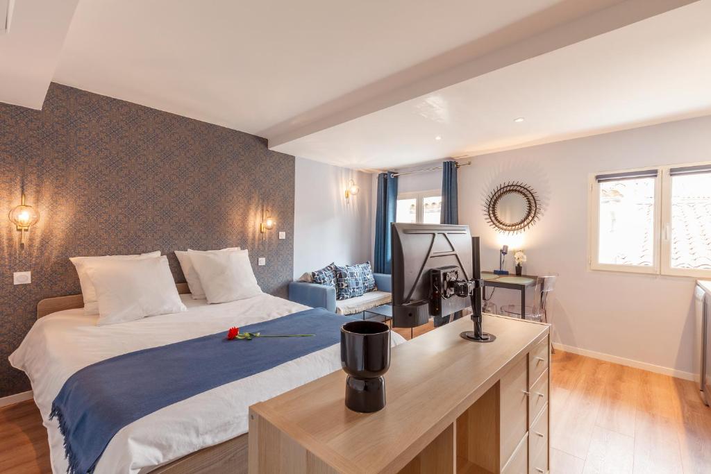 Un dormitorio con una cama y un escritorio con televisión. en Daumas 4 - Charme & Elégance, en Toulon