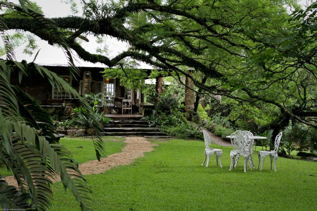 a statue of two chairs in the grass in front of a house at Reilly's Rock Hilltop Lodge in Lobamba