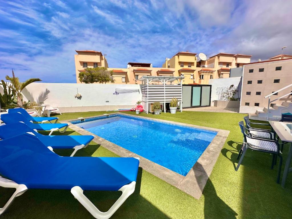 un cortile con piscina, sedie e una casa di El Mar House & Private Heated Pool ad Adeje