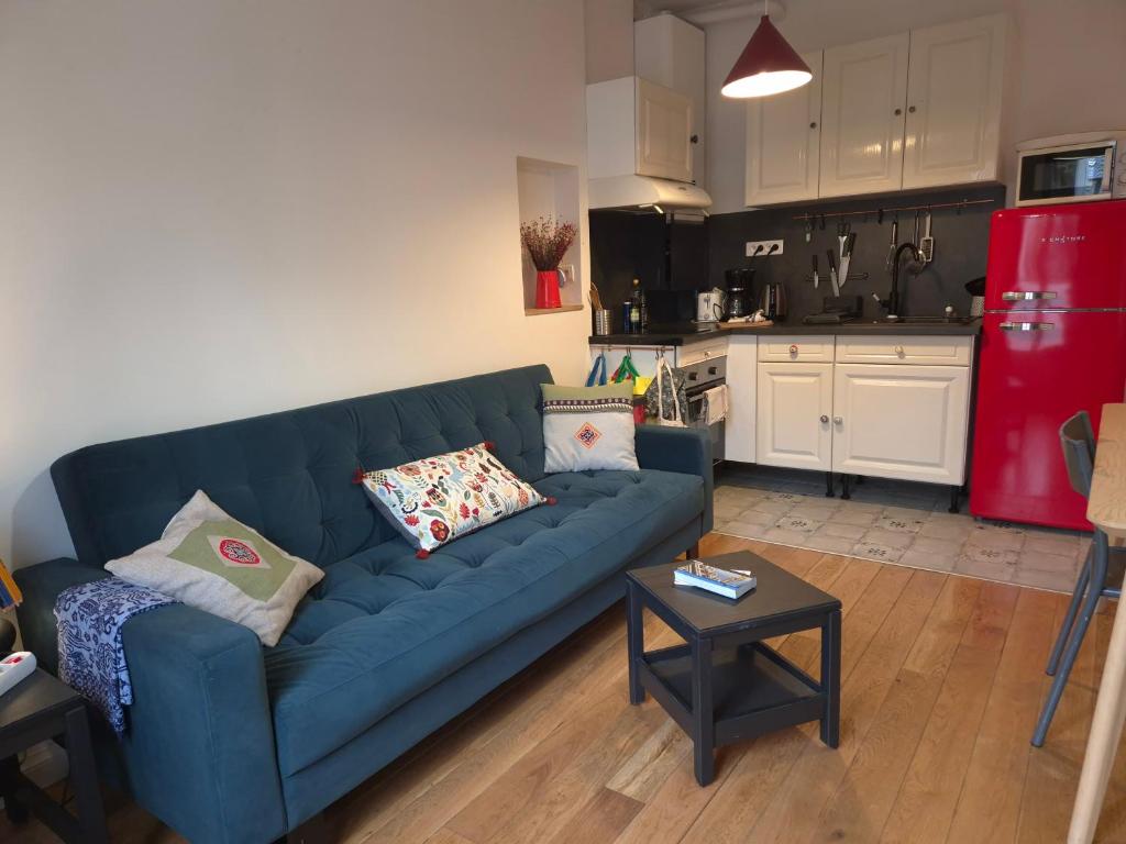 un salon avec un canapé bleu et une cuisine dans l'établissement Paris Stade de France, à Saint-Denis