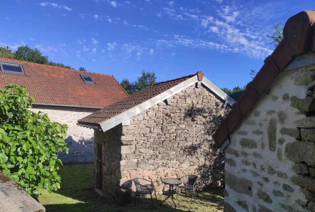 - un bâtiment en pierre avec des chaises dans une cour dans l'établissement Petit gite Pèlerin, à Jabreilles-les-Bordes