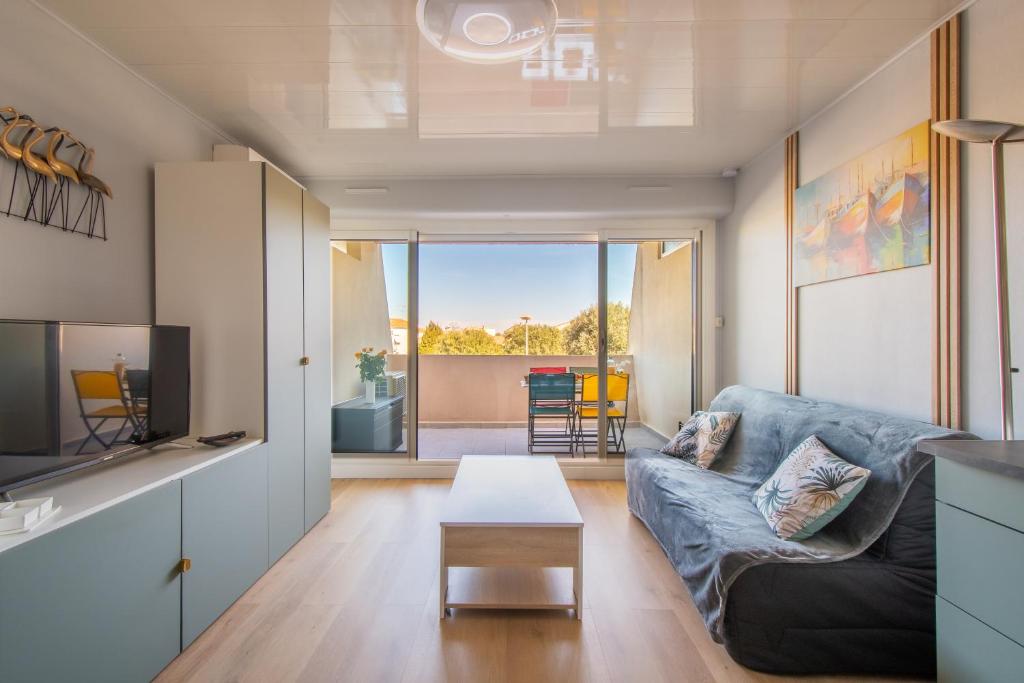 un salon avec un canapé et une table dans l'établissement L'Hacienda studio cosy 4 pers dans une résidence calme avec piscine belle terrasse coin nuit séparé à 300 m de la plage, au Grau-du-Roi
