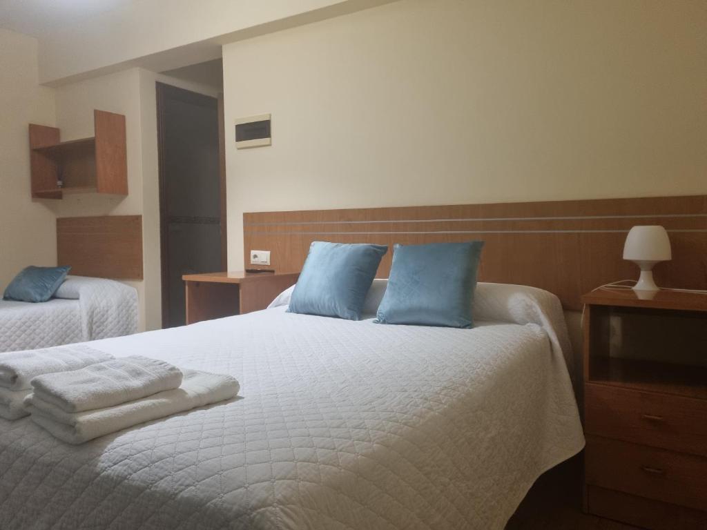 a bedroom with two beds with blue pillows at Hostal O Patron in Santiago de Compostela