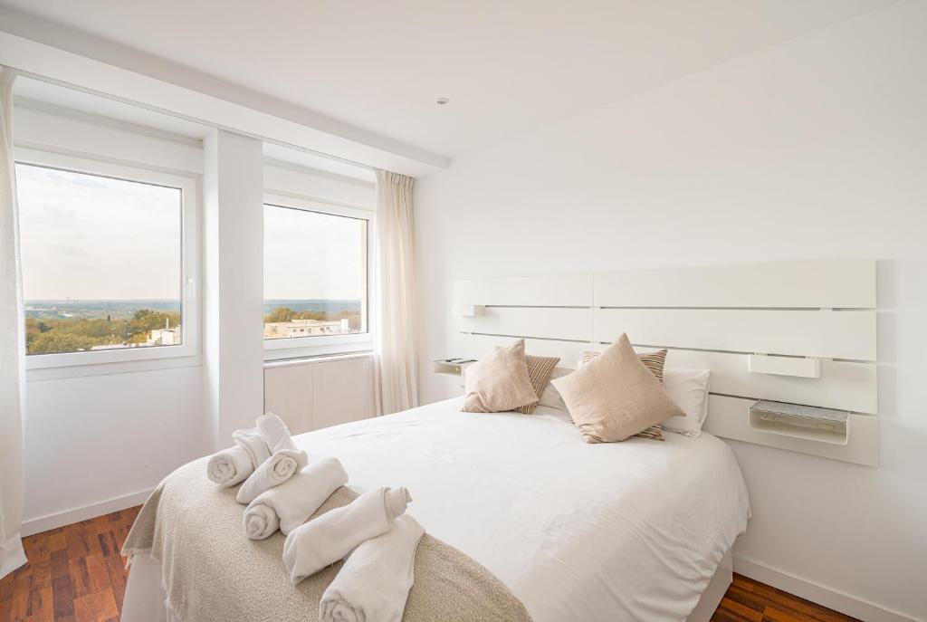 a white bedroom with a bed with towels on it at Plaza España Superb Views in Madrid
