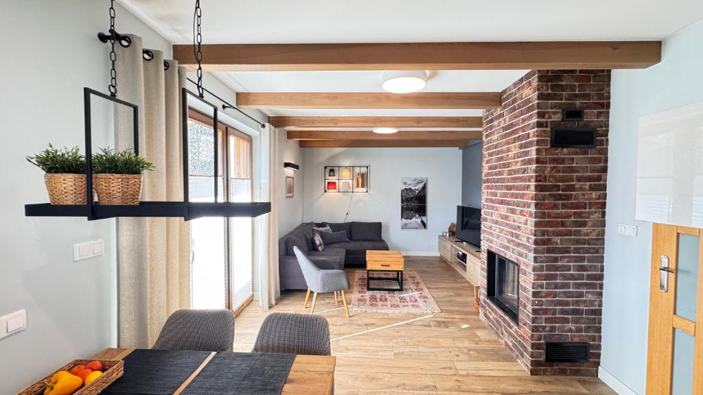 a living room with a brick fireplace and a couch at Przystanek Jaworki - Apartament w Jaworkach in Szczawnica