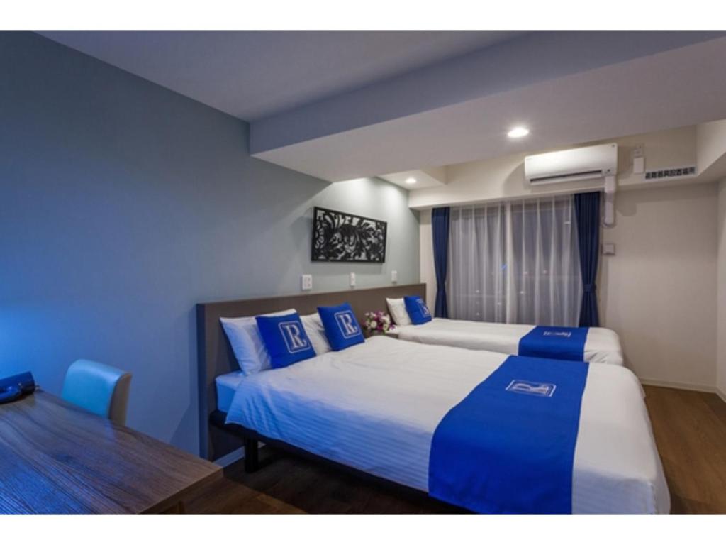 a bedroom with two beds with blue and white sheets at Condominium Resort Naha Living Inn Asahibashiekima - Vacation STAY 92450v in Naha