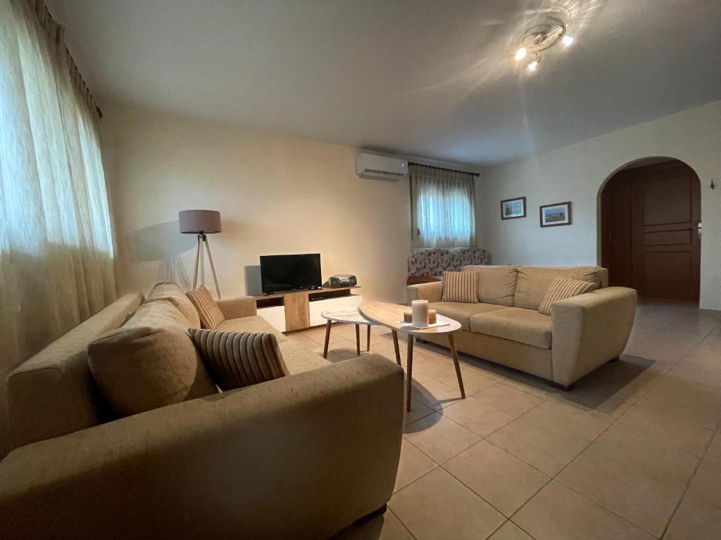 een woonkamer met twee banken en een tv bij Joanna's House in Néa Péramos