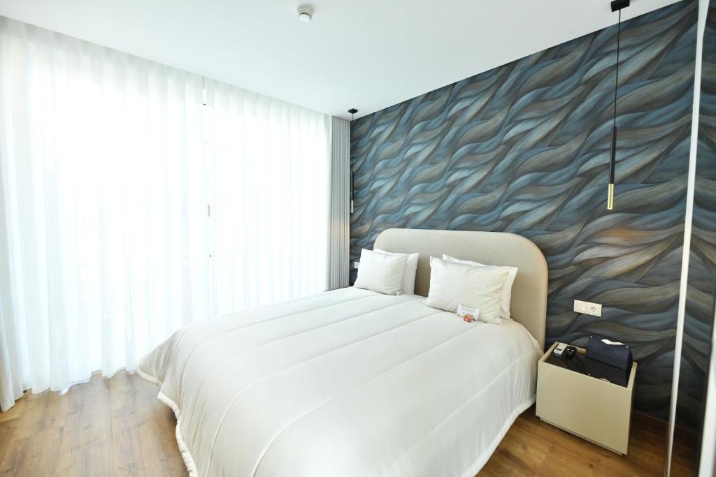 a bedroom with a large white bed and a wall with waves at Alojamento Dias in Tarouca