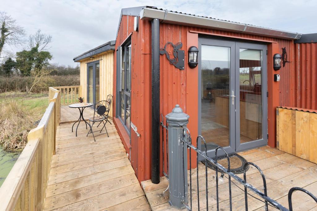 una casetta minuscola con terrazza con tavolo e sedie di Red Sheds Cabin 'Herons Den' a Portarlington