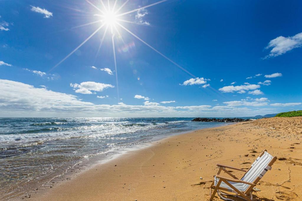 a beach chair sitting on a beach with the sun at Waipouli Beach Resort E301 in Kapaa