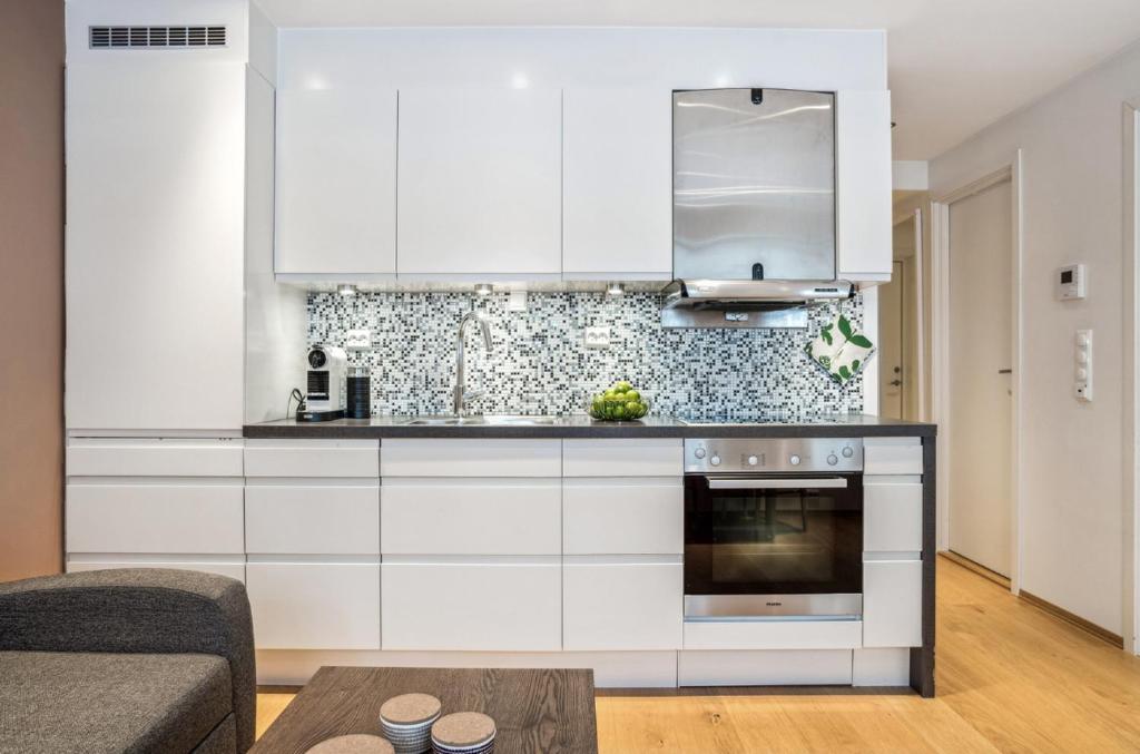 a kitchen with white cabinets and a stove at Stille leilighet med topp beliggenhet i Tromsø sentrum in Tromsø