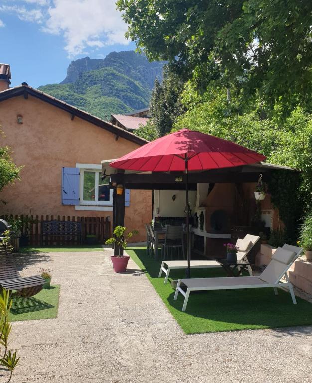 LantosqueにあるMon gîte à Pélasqueの赤いパラソル、テーブル、椅子付きのパティオ