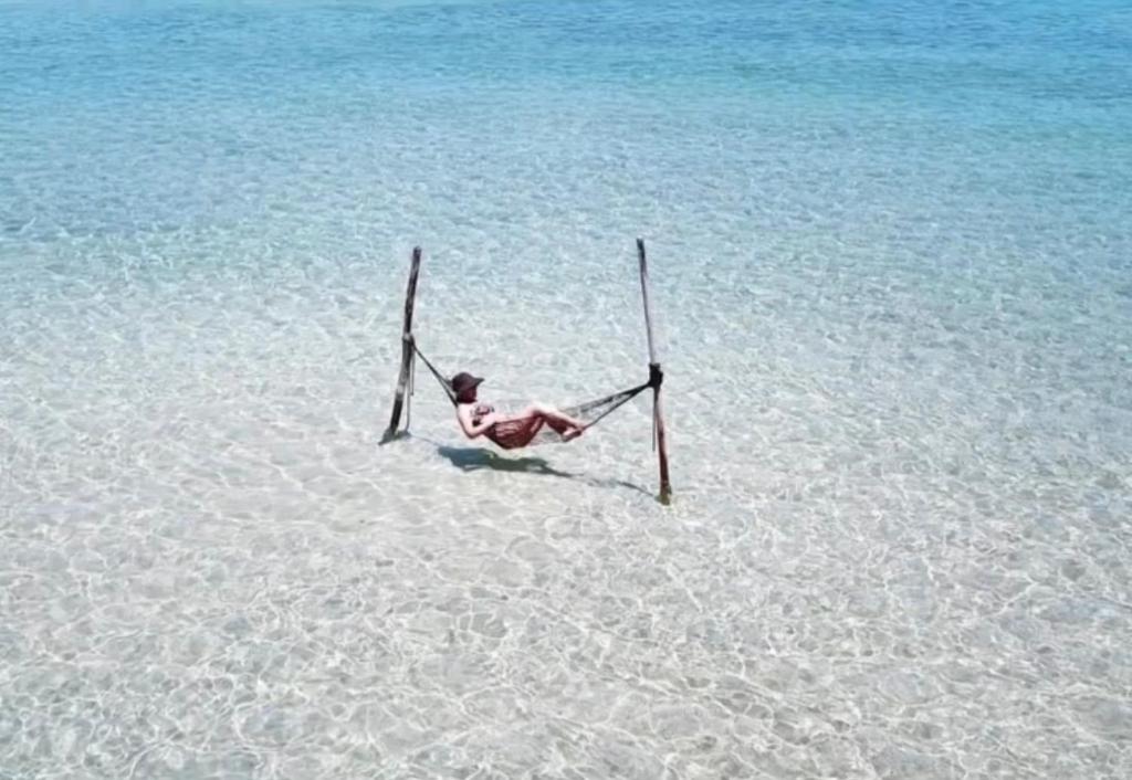 eine Person, die im Sand im Wasser liegt in der Unterkunft Cantinho do Rio in São Miguel dos Milagres