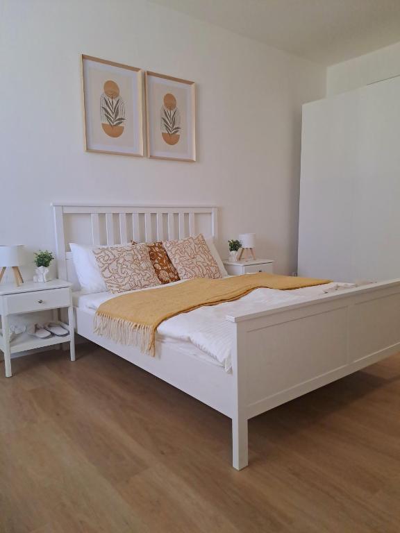 a white bed in a bedroom with two pictures on the wall at Apartman MWM Brno in Brno