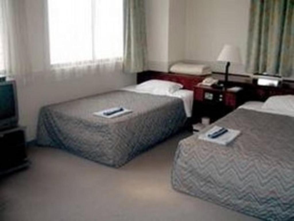 a hotel room with two beds and a television at Nakatsu Sunrise Hotel - Vacation STAY 64769v in Nakatsu