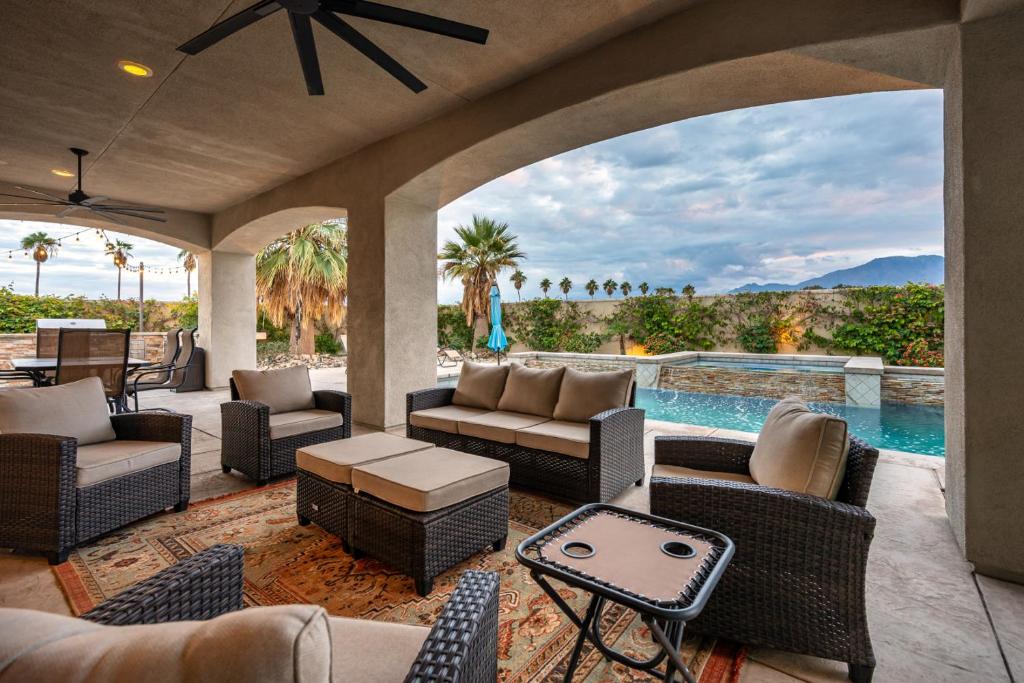an outdoor patio with a pool and chairs and a table at Coachella Dream - Luxury Mid-Term Rental in Indio