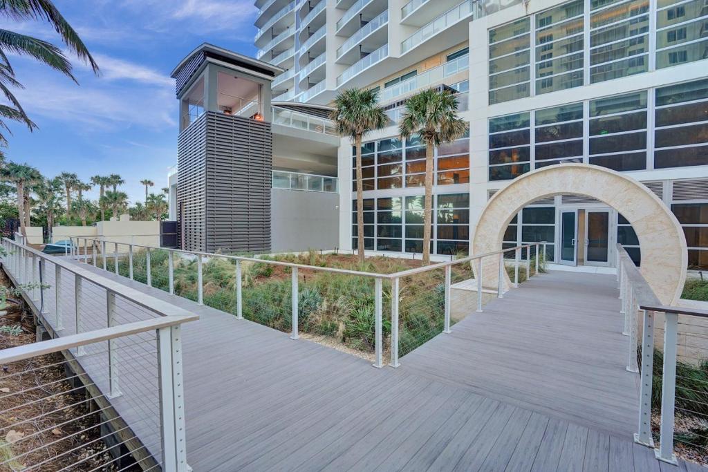 una passerella che conduce a un edificio con palme di Luxury Ocean View 2BR a Riviera Beach
