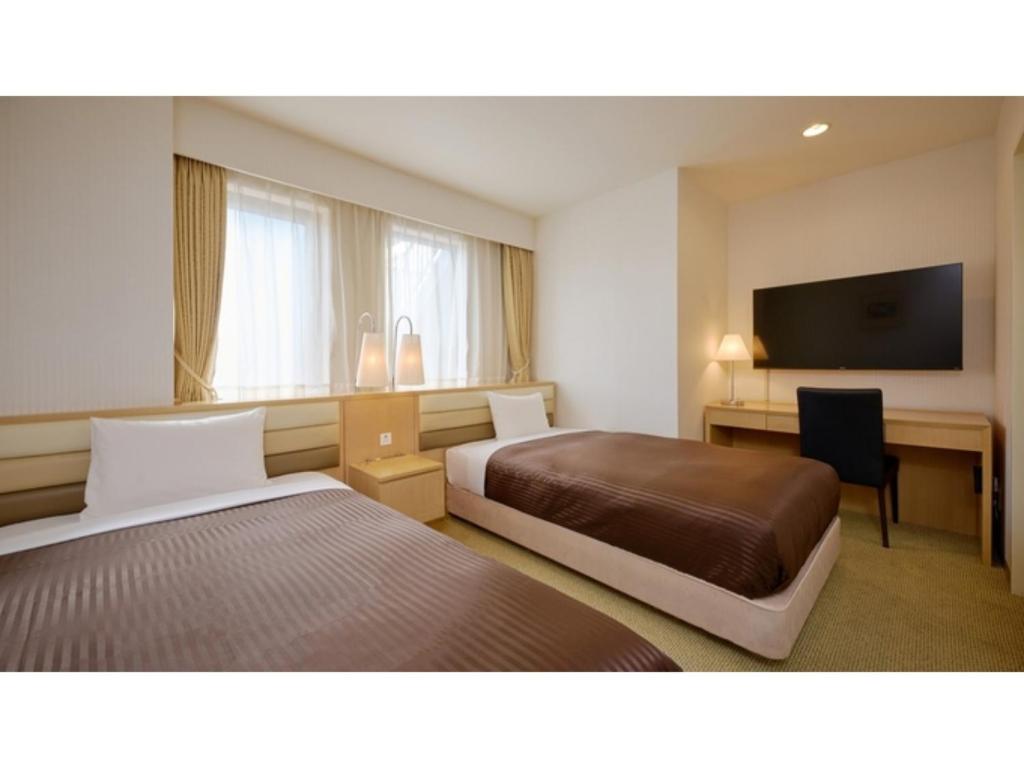 ein Hotelzimmer mit zwei Betten und einem Schreibtisch und einem Fernseher in der Unterkunft The OneFive Tokyo Kameido - Vacation STAY 64611v in Tokio